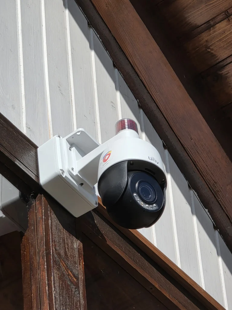 O camera de supraveghere exterior ptz unv instalata pe un perete.